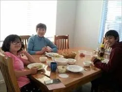 ホームステイゲストと楽しいディナータイム ホームステイゲストの女性とホストファミリーの子どもたちが夕食を囲む風景